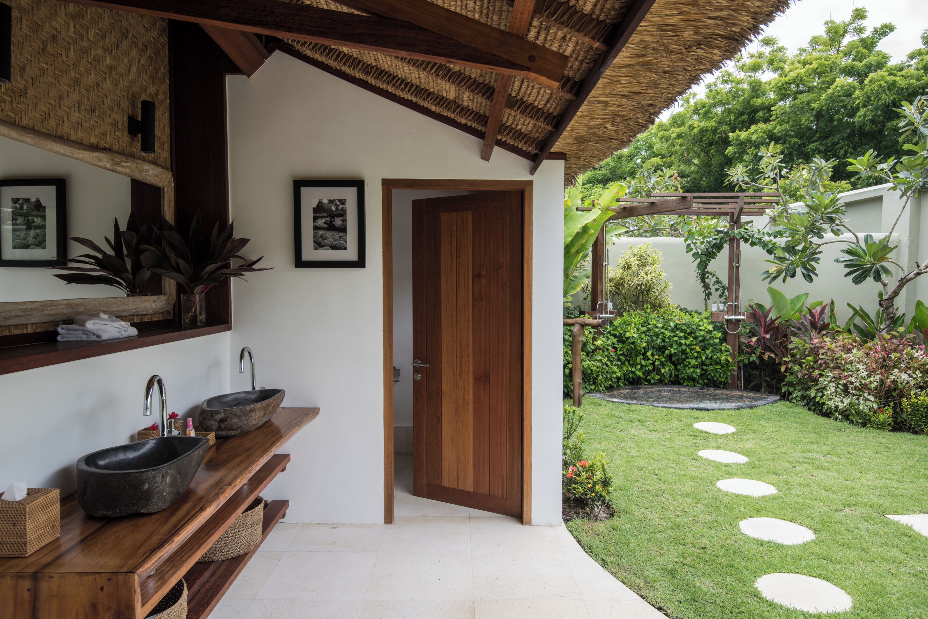 Casa de banho com toucador de madeira, duas pias e um espelho.