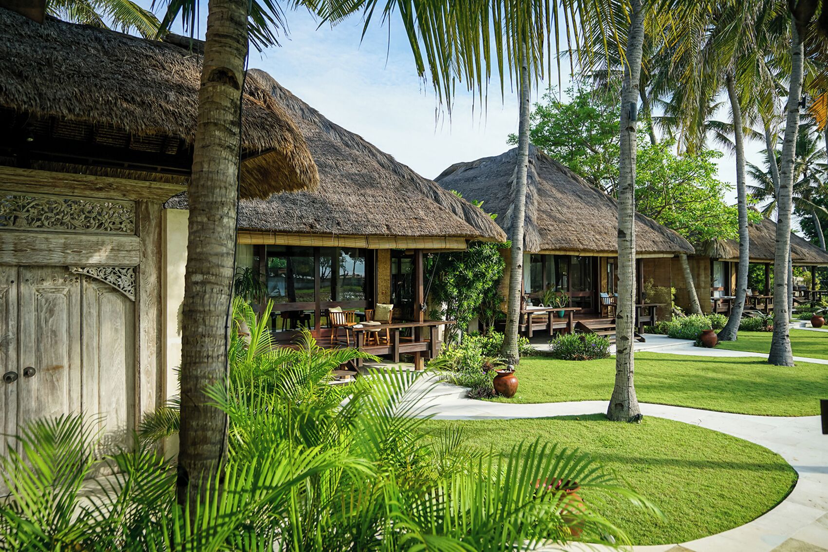 A resort with thatched-roof buildings, outdoor seating, and lush greenery.