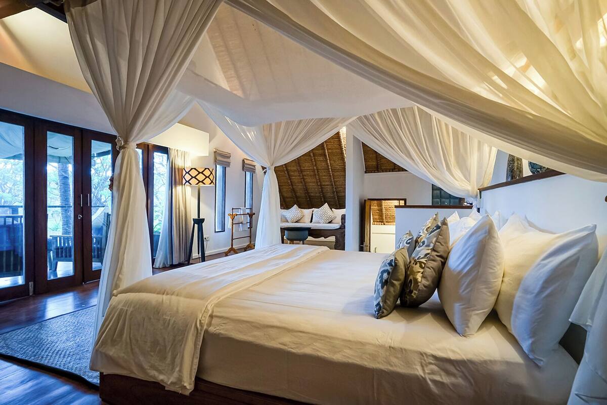 A spacious bedroom with a large bed, a canopy, and a view of the outdoors.