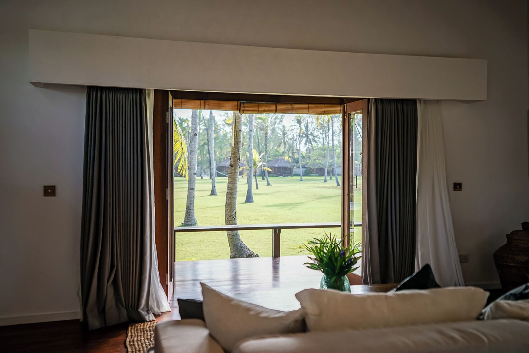 A room with a large window, a sofa, and a potted plant.