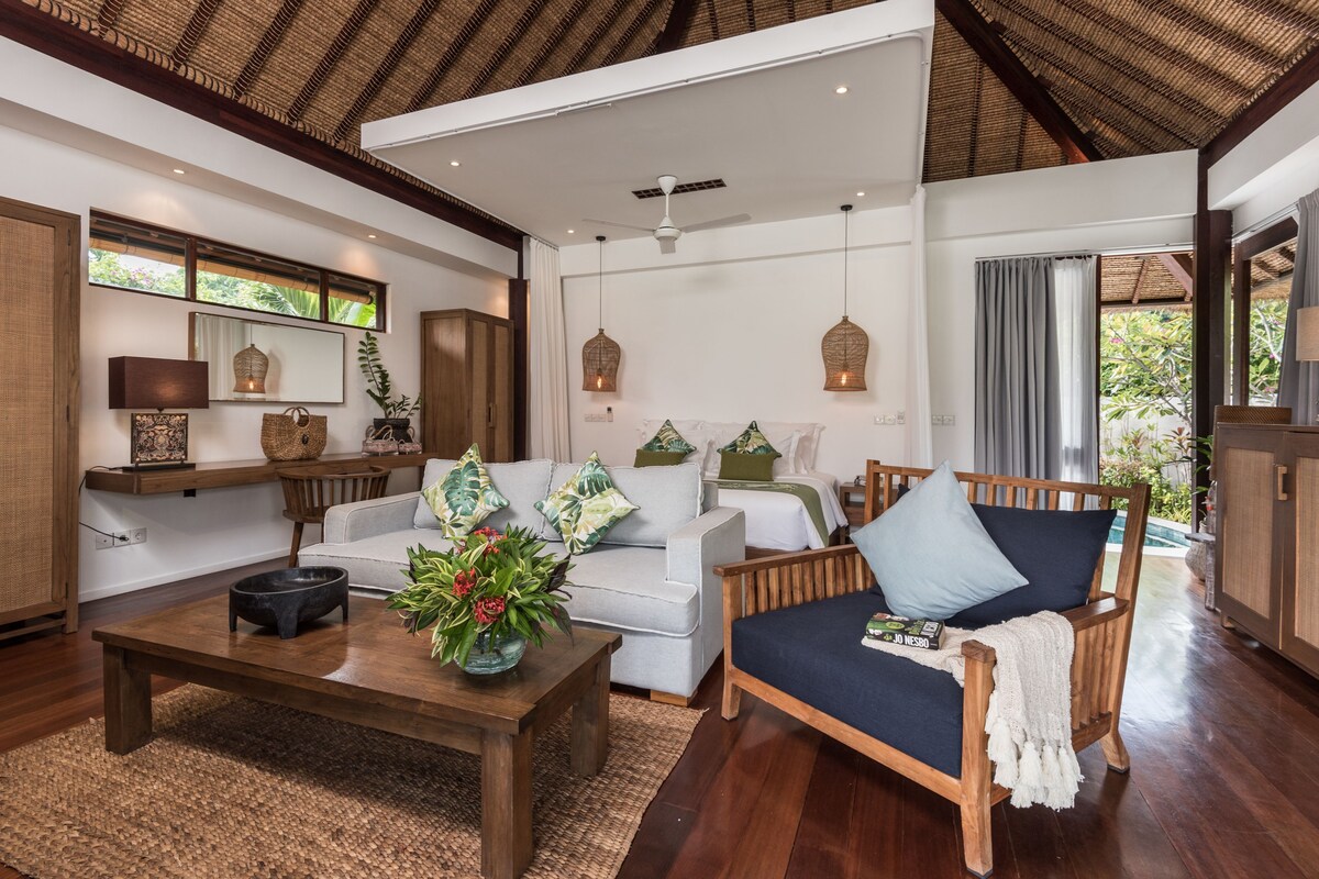 A living room with a sofa, a coffee table, wicker lamps, and a ceiling fan.