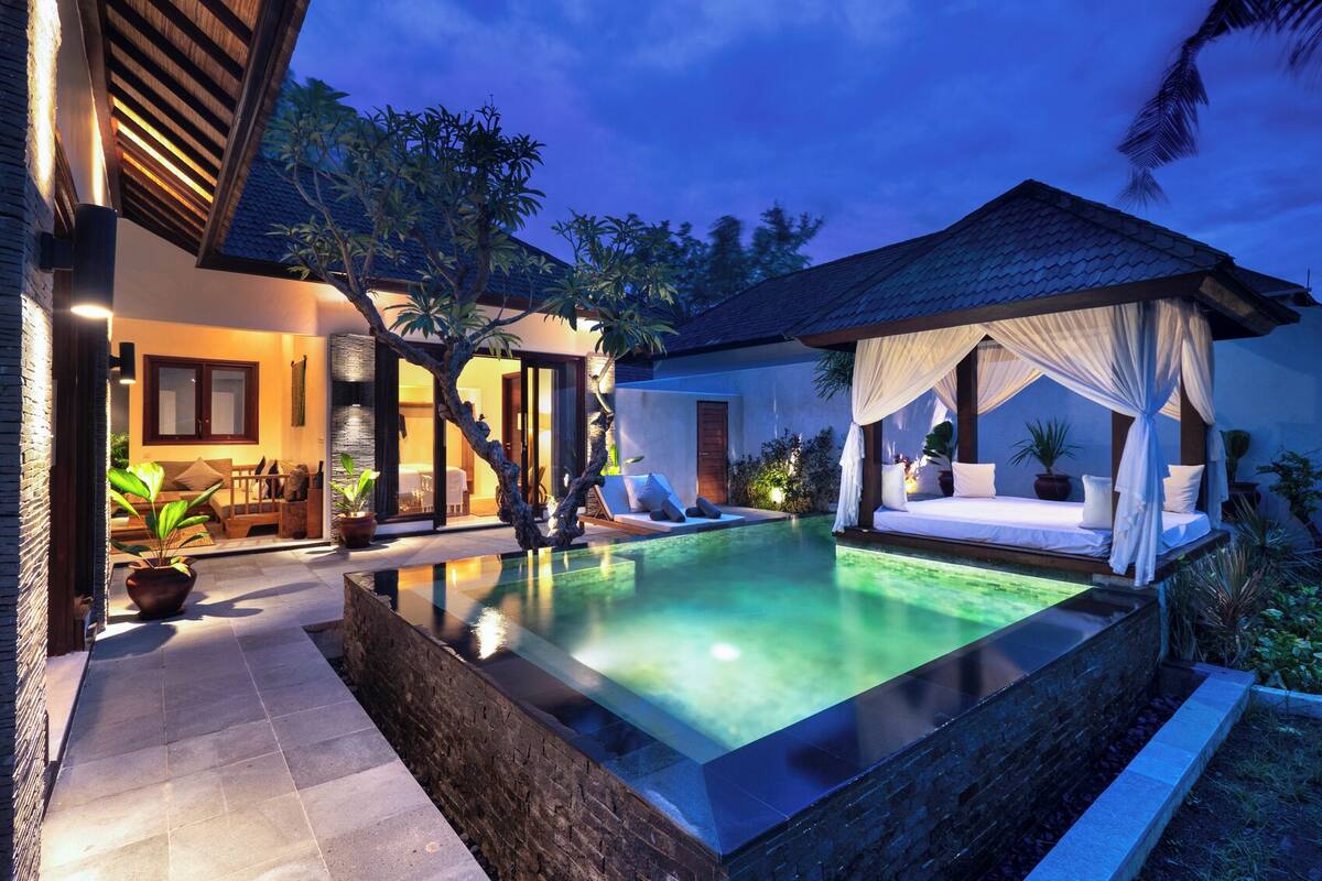 A poolside area with a canopy, a lounge chair, and a small table.