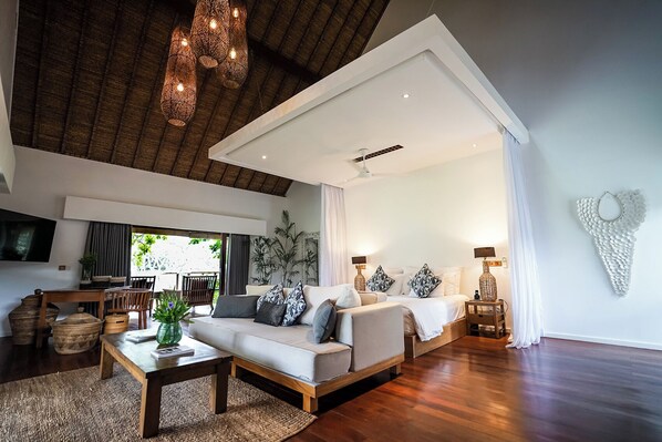 A spacious living room with a high ceiling, a sofa set, a coffee table, and a television.