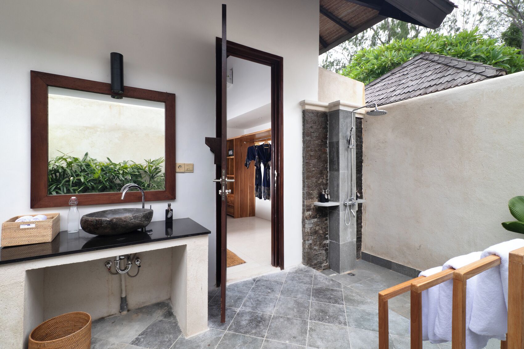 A bathroom with a stone sink, a mirror, and a shower area.