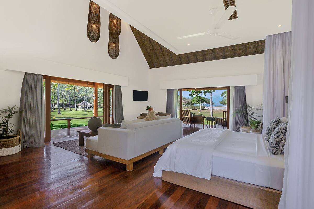 A spacious bedroom with a large bed, a sofa, and a television.