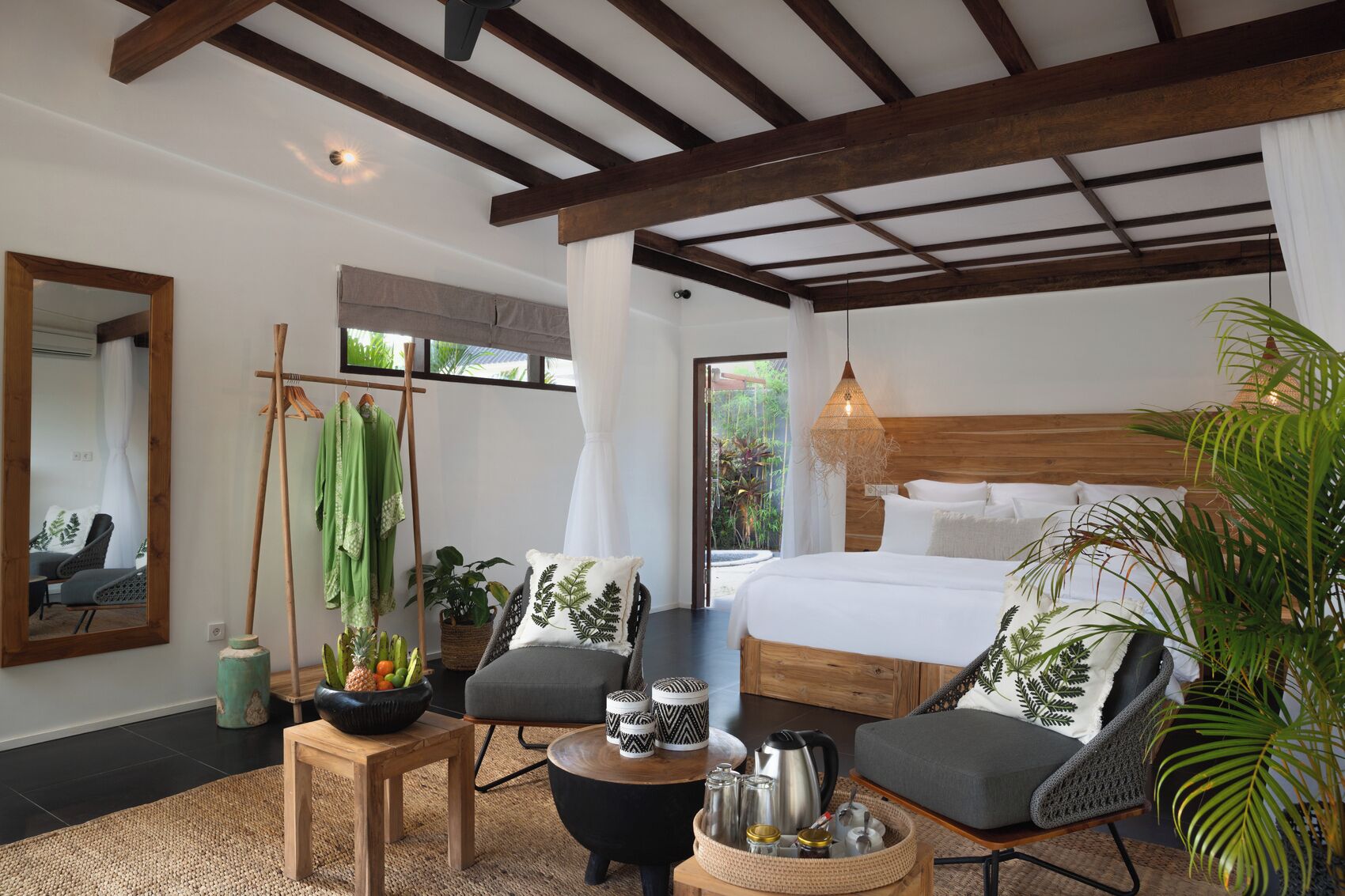 Une chambre à coucher comprenant un lit, deux chaises, une petite table, un luminaire suspendu et une grande fenêtre.