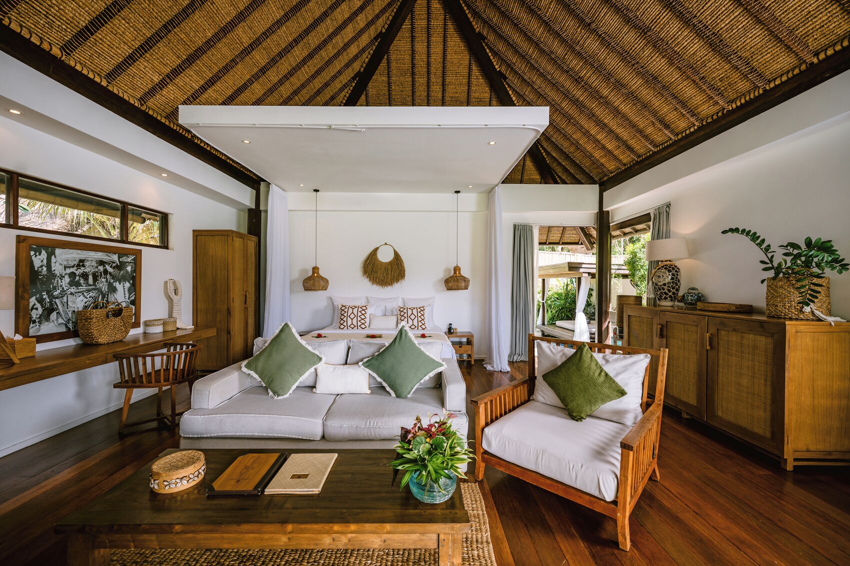 A spacious living area with a high ceiling, a sofa set, a coffee table, and a view of the outdoors.