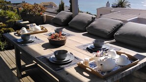 A wooden deck with a table set for breakfast overlooking the sea. - Fijnbos Private Manor (Cape Town)