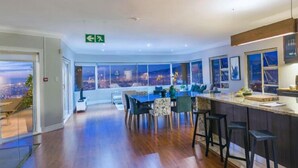 A modern dining area with a city view, a bar with stools, and a large window overlooking the cityscape. - Fijnbos Private Manor (Cape Town)