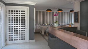 A modern kitchen with a copper countertop, striped wall panels, and a seating area with a cushioned bench and a table. - Fijnbos Private Manor (Cape Town)