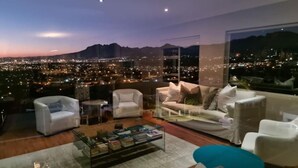 A modern living room with a city view, featuring a sofa, armchairs, and a coffee table. - Fijnbos Private Manor (Cape Town)