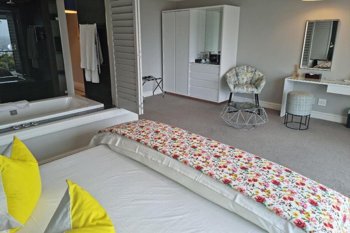 Una habitación de hotel con una cama, una silla, un tocador y un espejo grande.