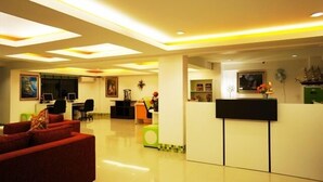 Un moderno vestíbulo de hotel con recepción, zona de estar y comedor.