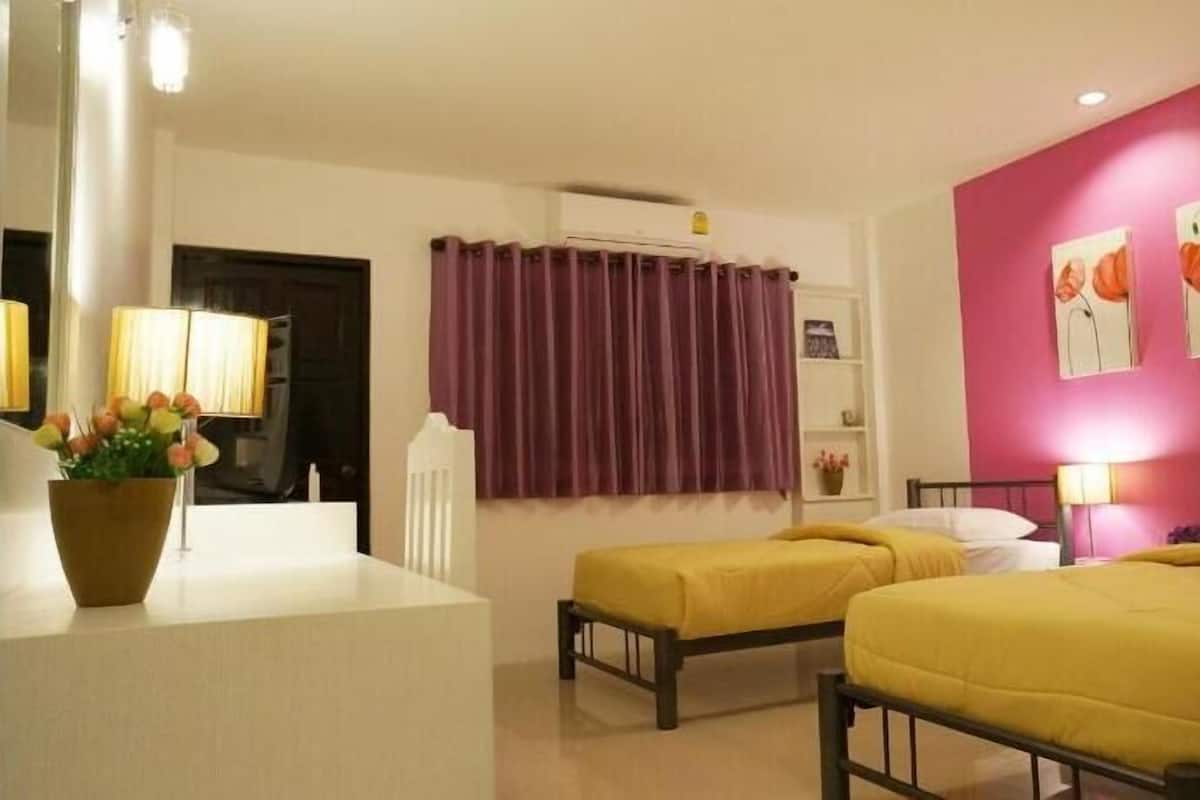 Habitación de hotel con dos camas, un escritorio, una silla, una ventana con cortinas y una pared decorada con obras de arte.