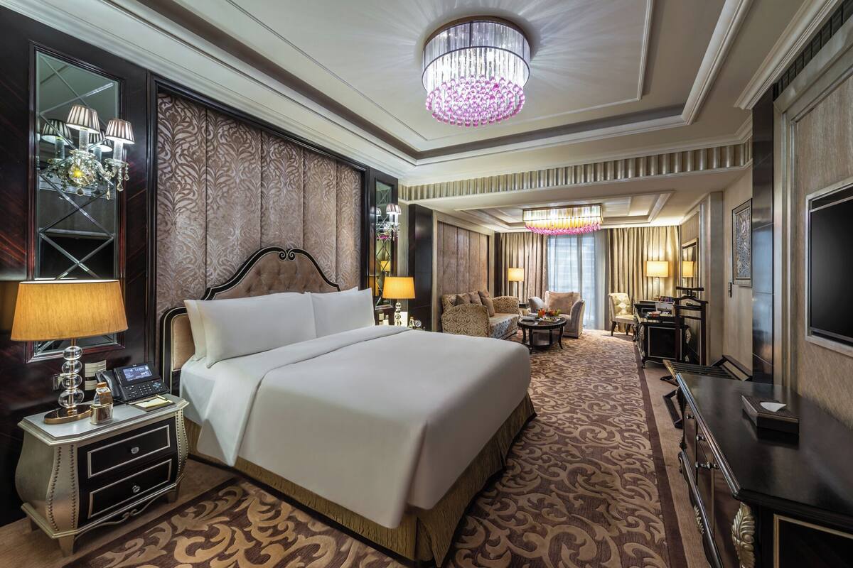 A spacious hotel room with a large bed, a desk, a chair, and a television.