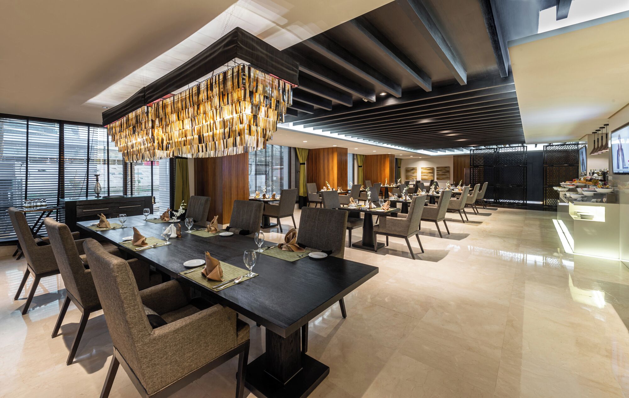 A modern dining area with a long table set for a meal, surrounded by chairs.