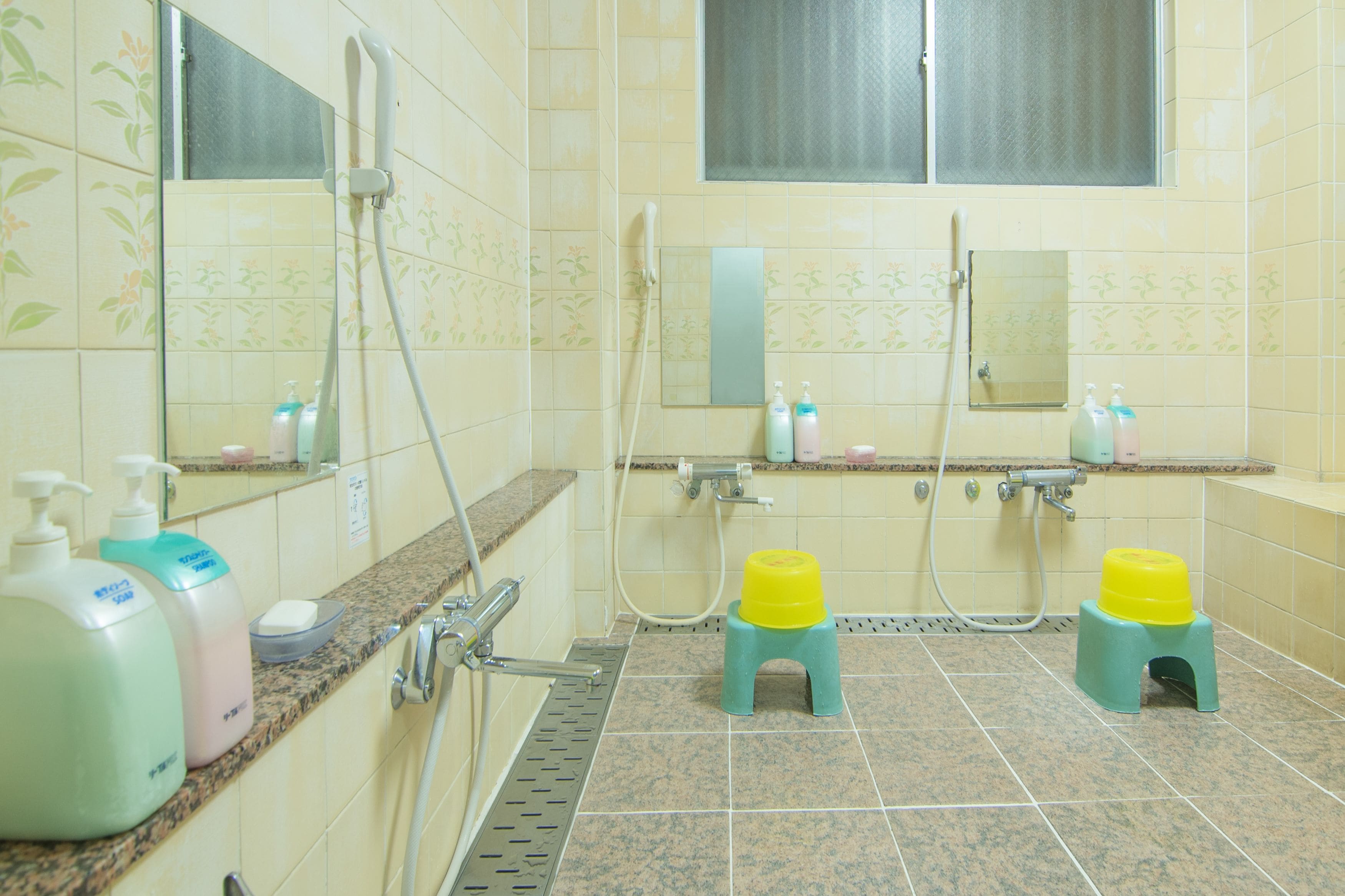 A bathroom with a shower, a sink, and two small stools.