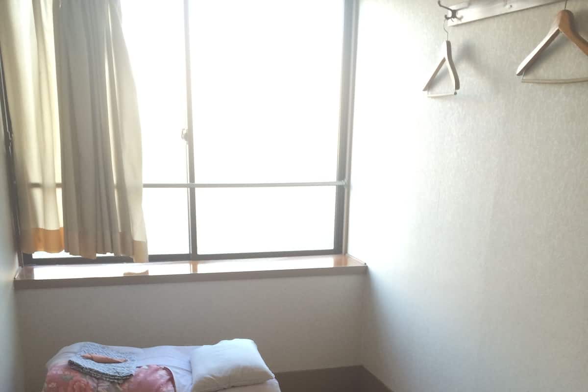 A room with a bed, a small table, and a window with curtains.