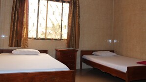 A room with two wooden beds, a wooden nightstand, and a window with curtains. - Lucky 1 Guesthouse (Phnom Penh)