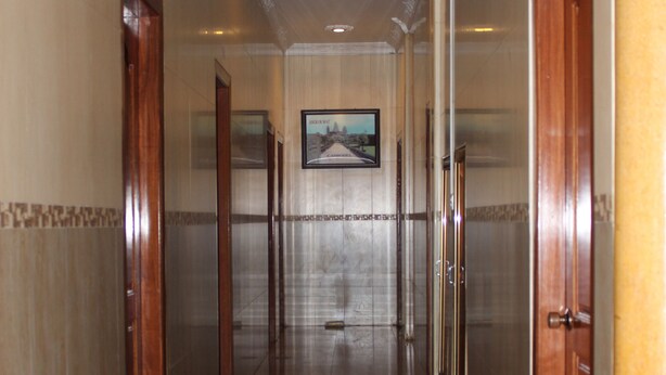 A corridor with doors on both sides, a tiled floor, and a framed picture on the wall. - Lucky 1 Guesthouse (Phnom Penh)