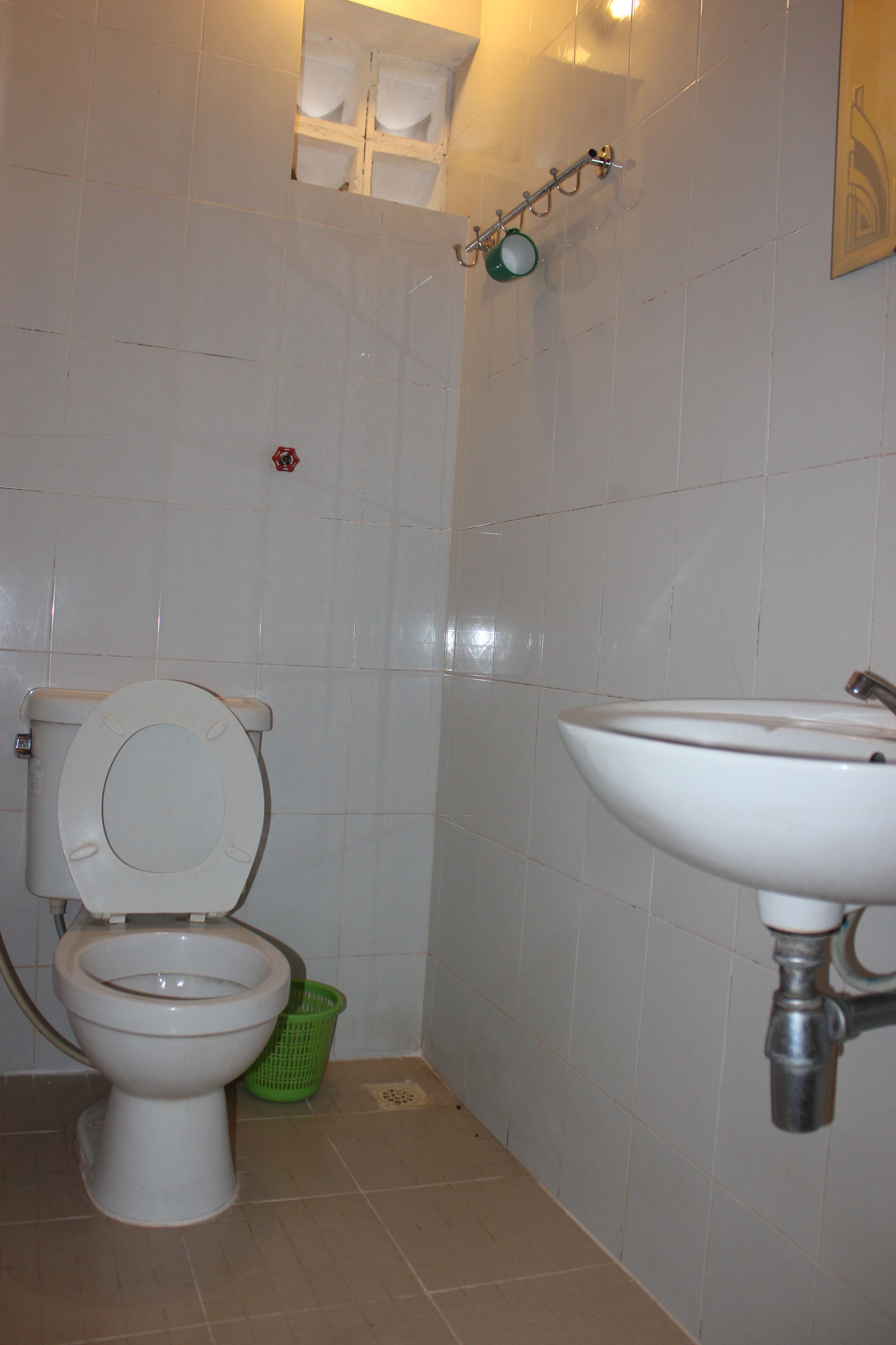Un baño con inodoro, lavamanos y una cesta verde.