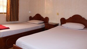 Una habitación de hotel con dos camas individuales, una mesita de noche de madera y una ventana con cortinas.
