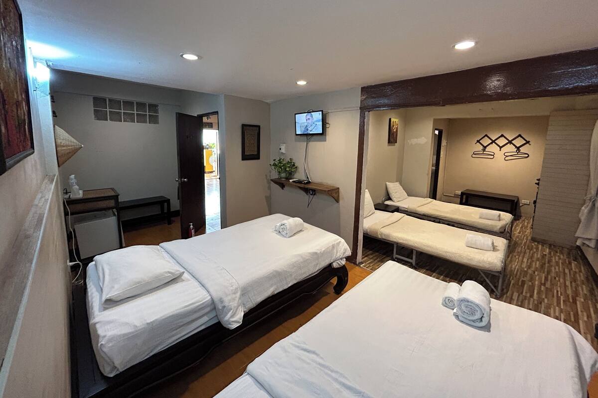 A hotel room with two beds, a TV, a small table, and a mirror.