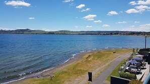A lakeside view with a grassy area, a path, and outdoor seating. - Boulevard Waters (Taupo)