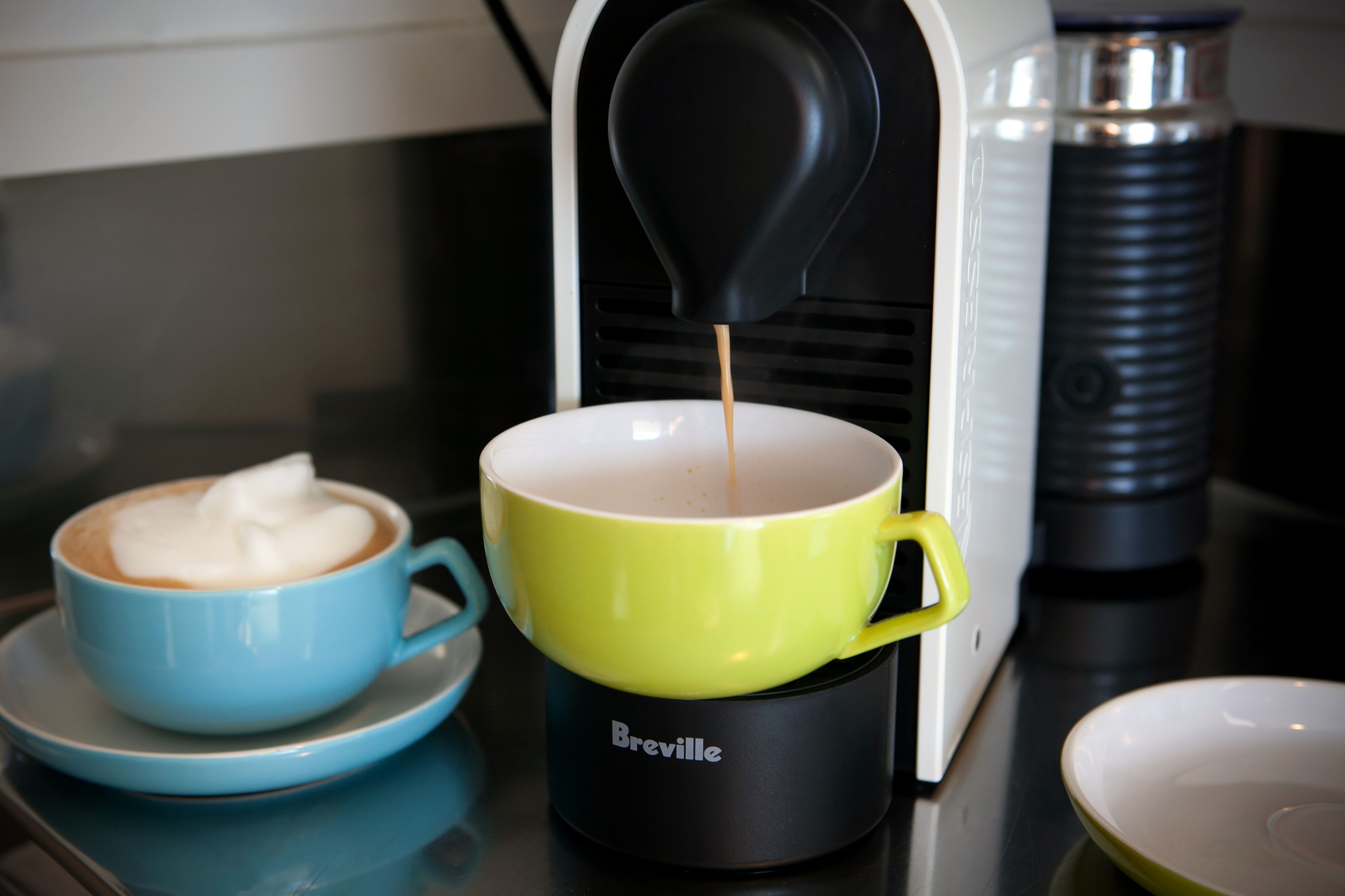 Una máquina de café sirviendo café en una taza amarilla.