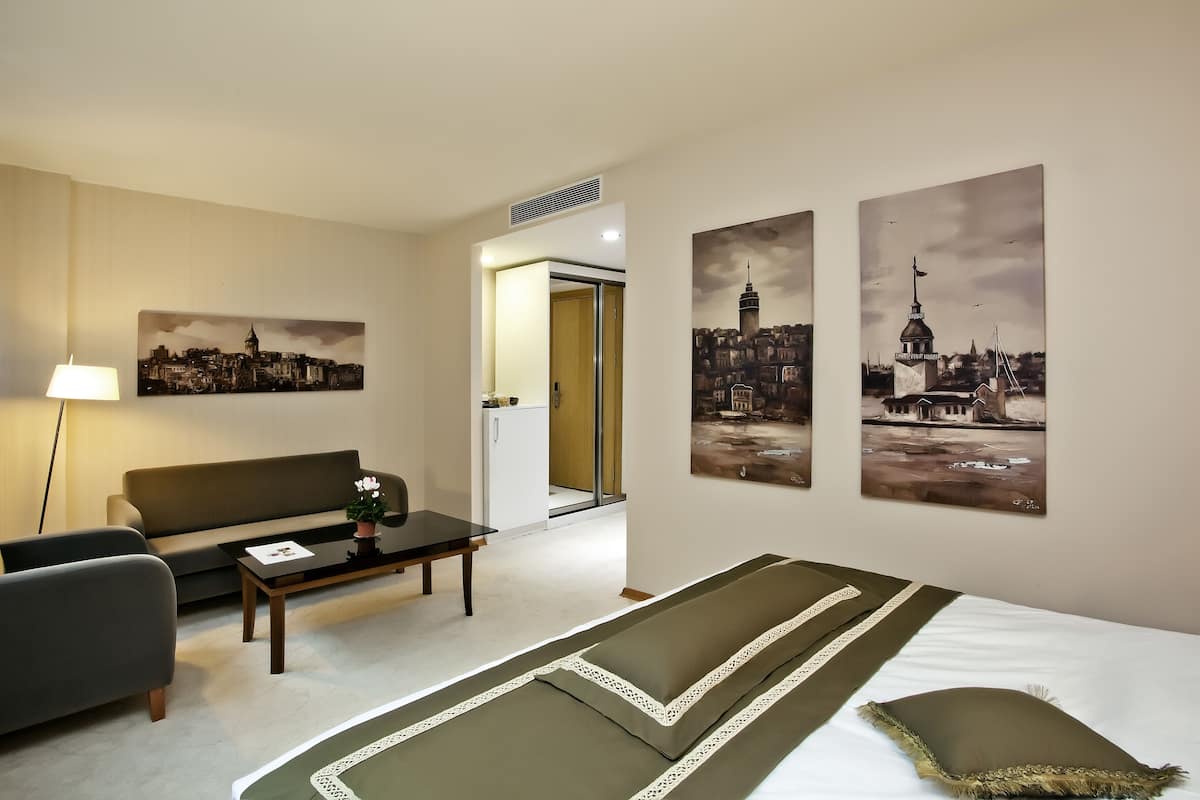 Une chambre d’hôtel comprenant un lit, un canapé, une table basse et deux tableaux accrochés au mur.