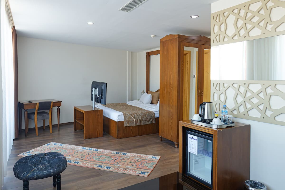 Une chambre d’hôtel avec un lit, un bureau, une chaise, une télévision et une petite table.