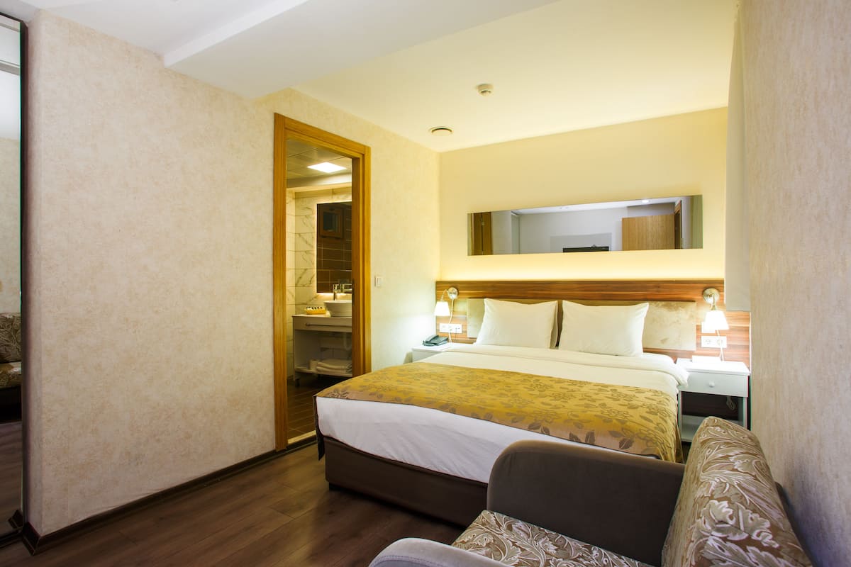 Une chambre d’hôtel comprenant un lit, des tables de chevet, un miroir et une armoire.