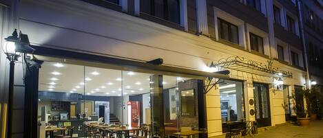 A restaurant with outdoor seating, large windows, and a brick wall interior.