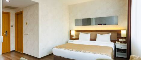 Une chambre d’hôtel avec un grand lit, des tables de chevet, un bureau avec une chaise et un téléviseur.