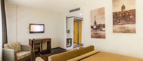 A hotel room with a bed, a sofa, a desk, a television, and artwork on the walls.