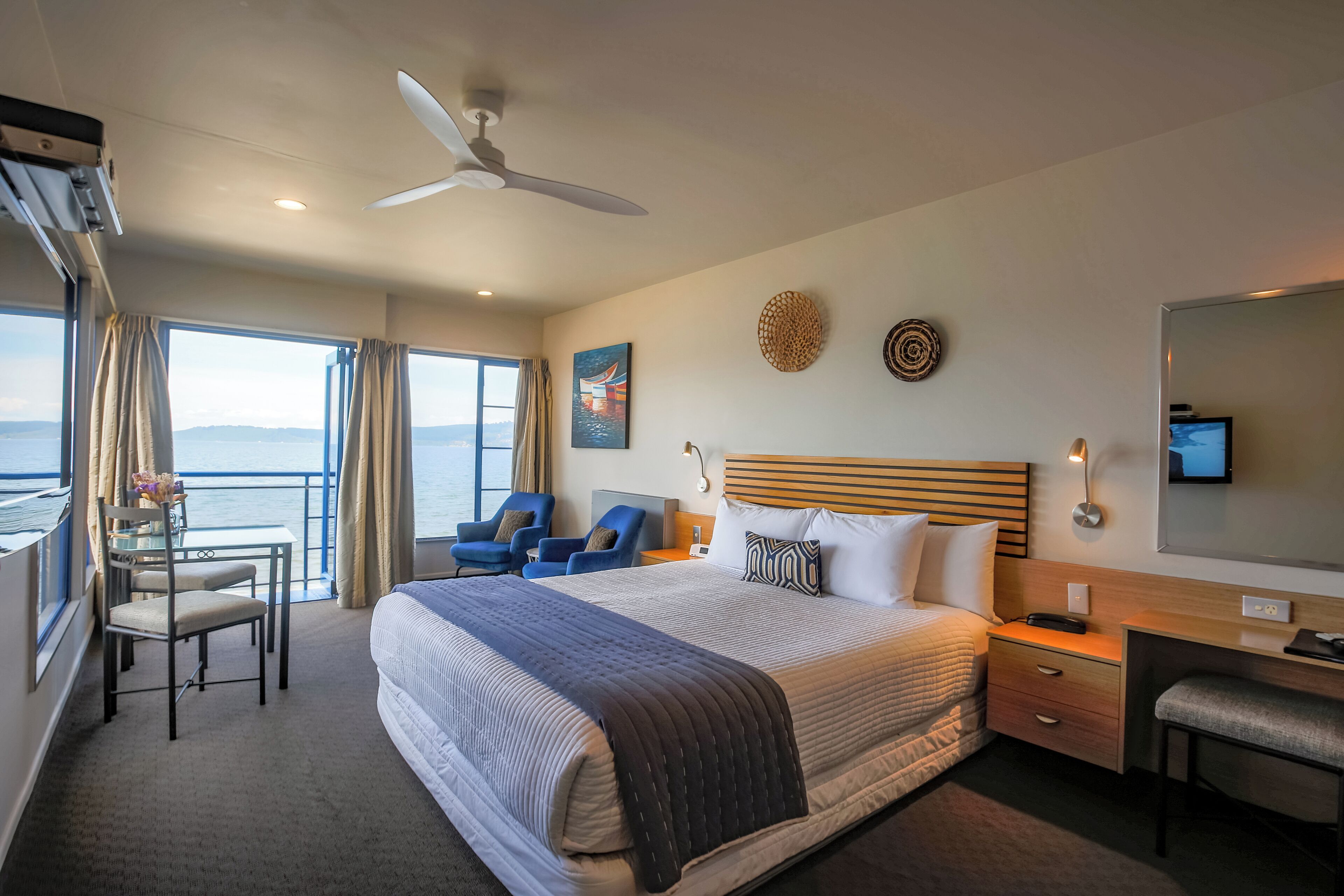 Une chambre d’hôtel avec un grand lit, un bureau, une chaise, une télévision et une vue sur la mer.