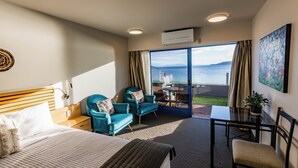 Una habitación de hotel con cama, escritorio, silla, mesita y vistas al mar.