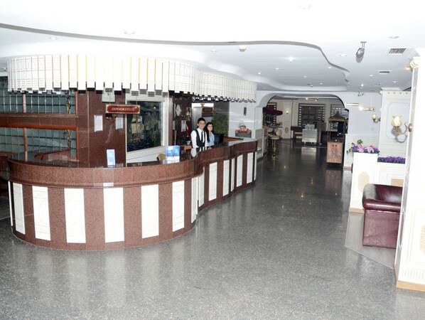 A reception area with a curved counter, a sign labeled "Information," and a seating area with a cushioned bench. - Sevcan Hotel (Istanbul)
