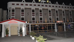Un hotel con un llamativo letrero 'SEVCAN', un restaurante y un bar cafetería.