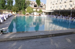 Una piscina rectangular amb un marc de rajola, envoltada per una paret de pedra baixa.