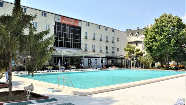 Un hotel con piscina, mobiliario exterior y una zona cubierta.
