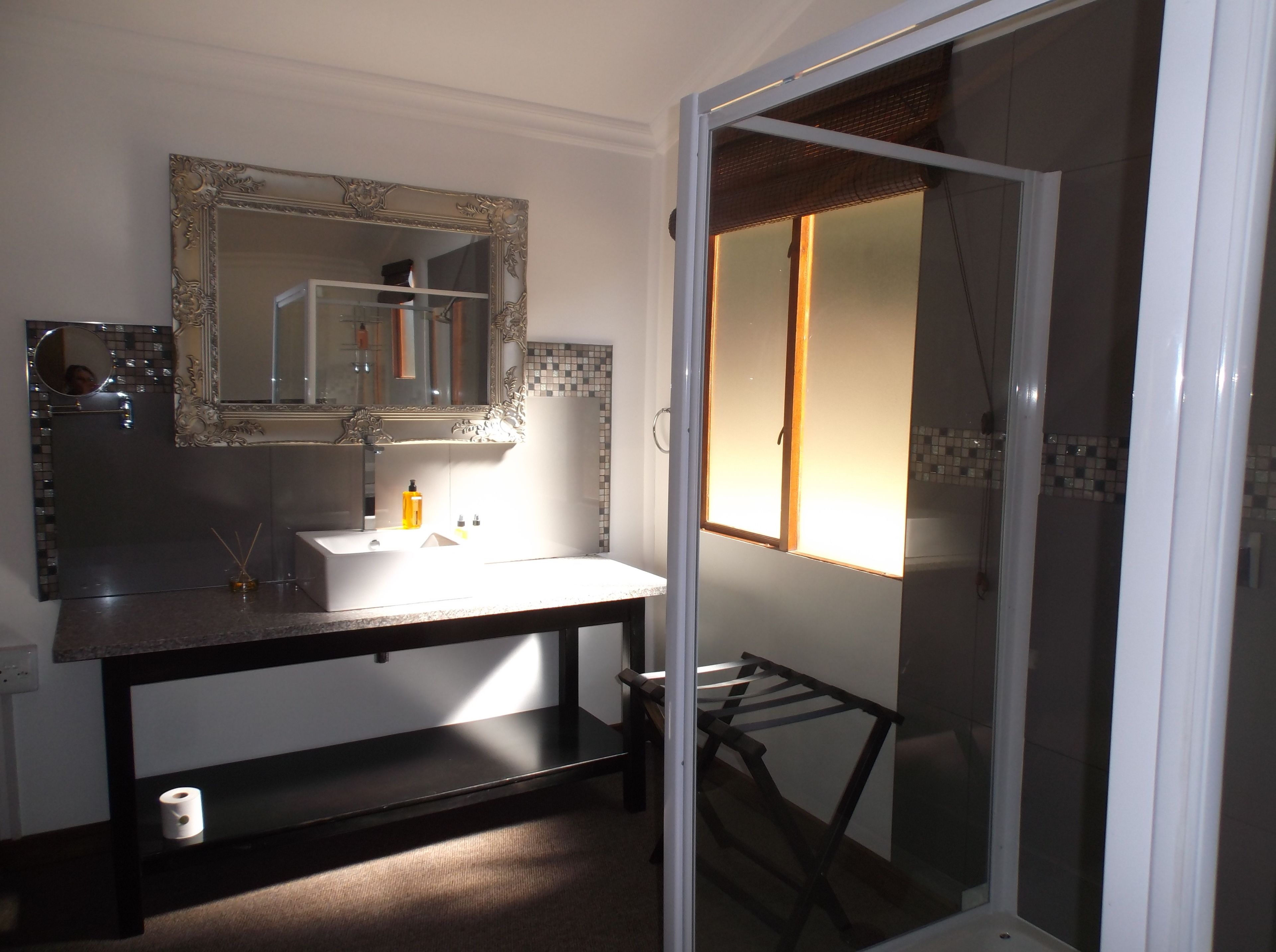 A bathroom with a sink, mirror, and shower.