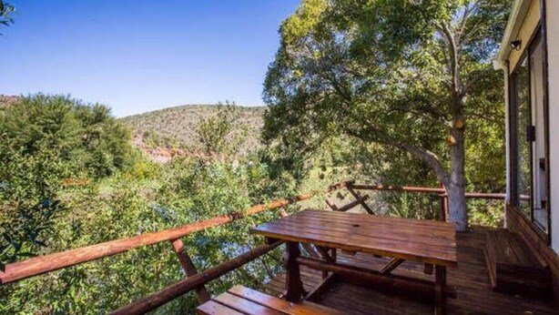 Une terrasse en bois avec une table de pique-nique, offrant une vue sur un paysage verdoyant et vallonné.