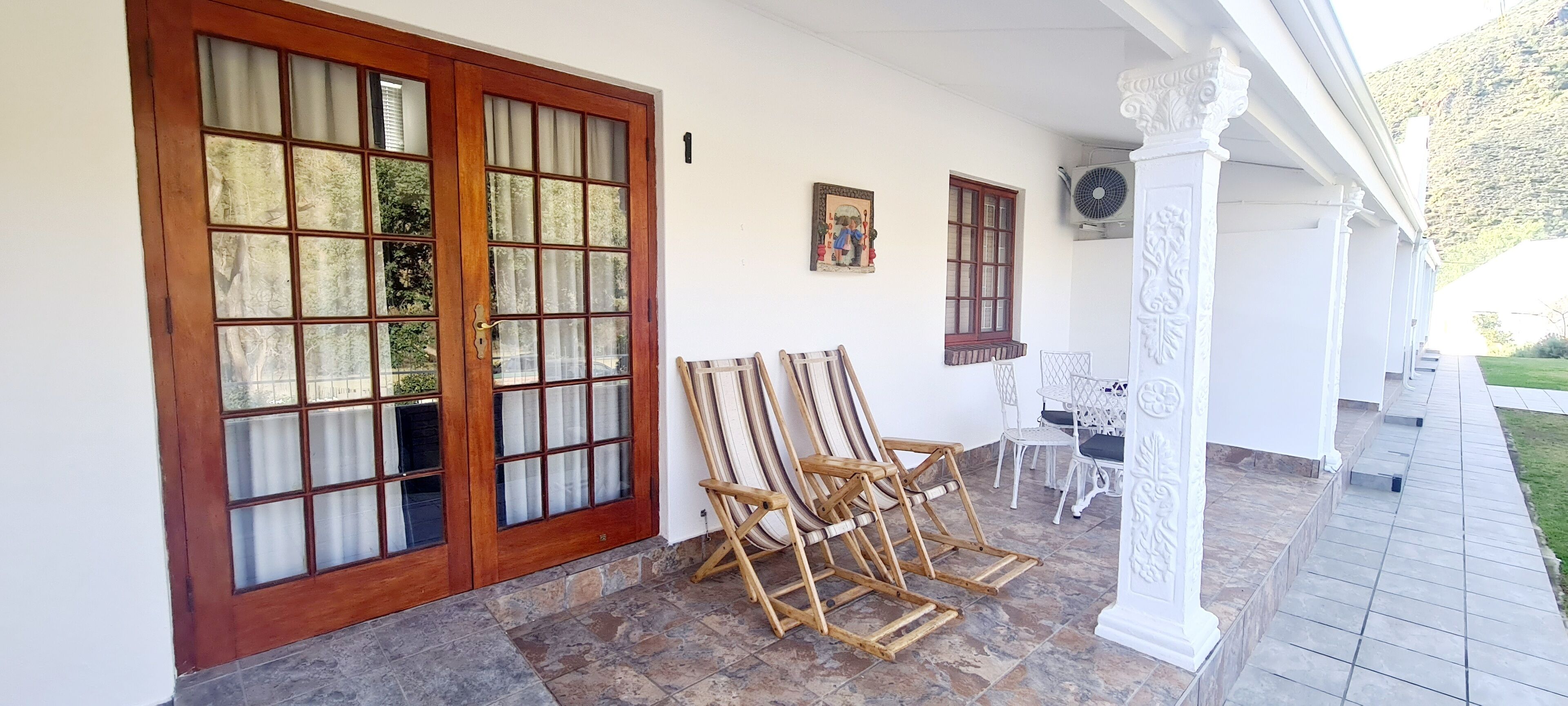 A covered porch with a large wooden door, two windows, and a small table with chairs.