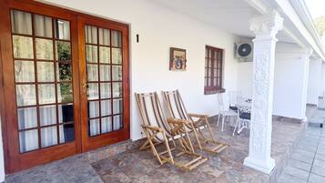 A covered porch with a large wooden door, two windows, and a small table with chairs.