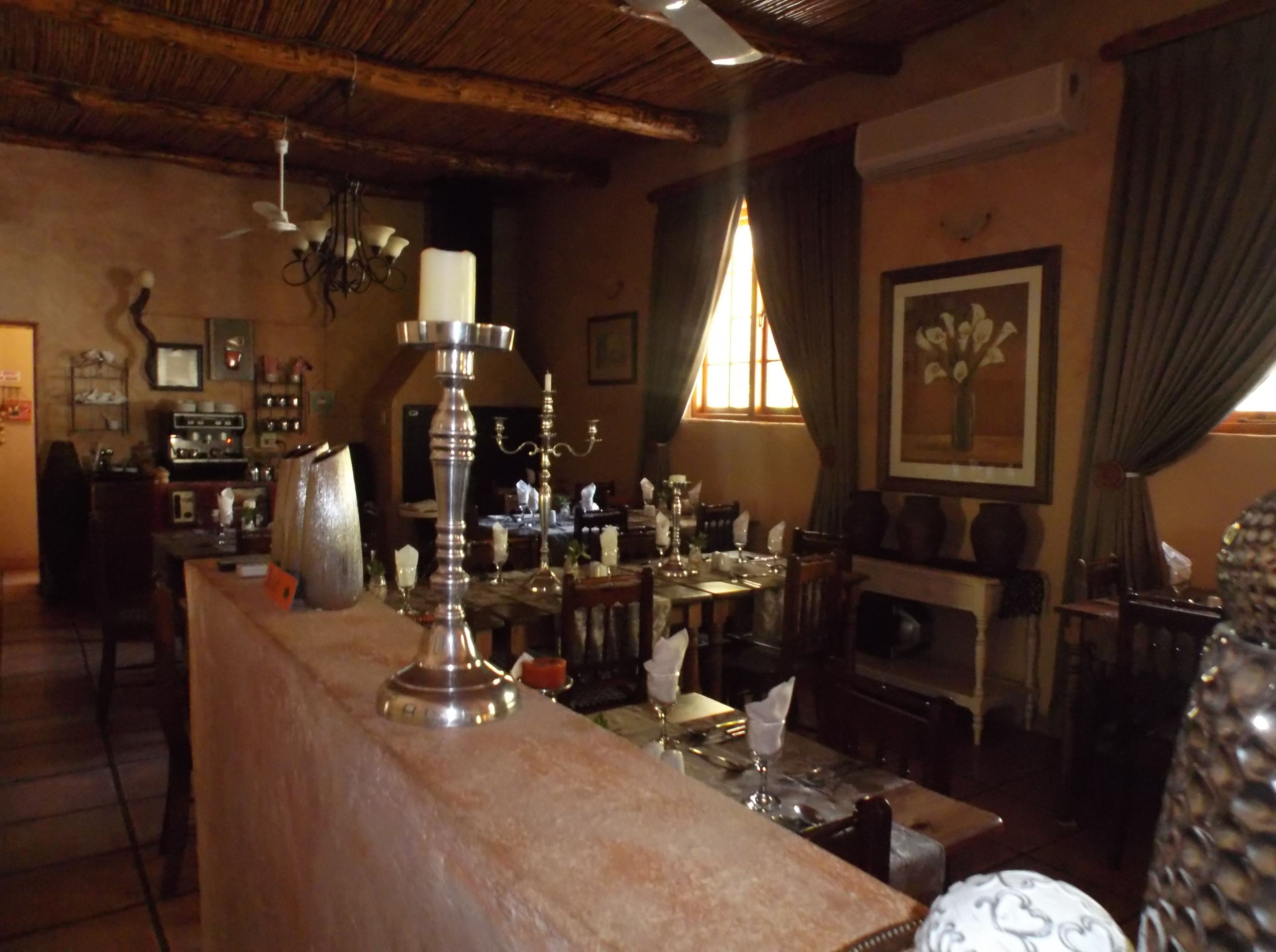 A cozy, rustic dining area with a wooden ceiling, a large chandelier, and a bar counter.