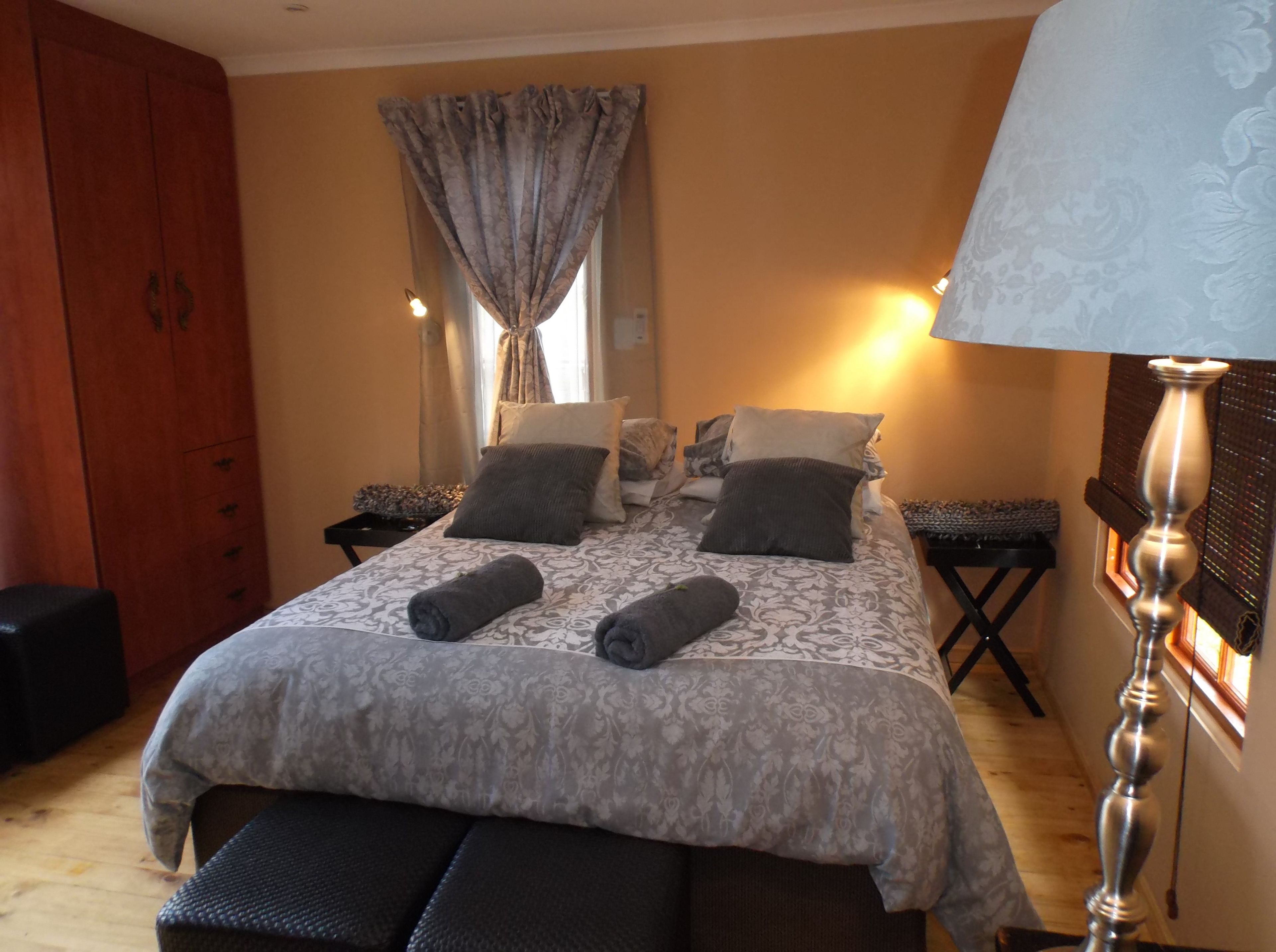 A neatly arranged bedroom with a bed, bedside tables, a wardrobe, and a lamp.