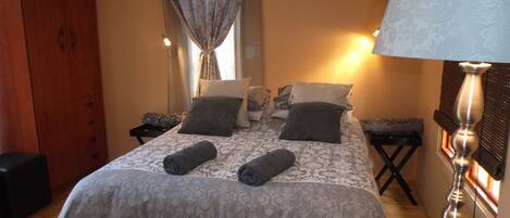 A neatly arranged bedroom with a bed, bedside tables, a wardrobe, and a lamp.