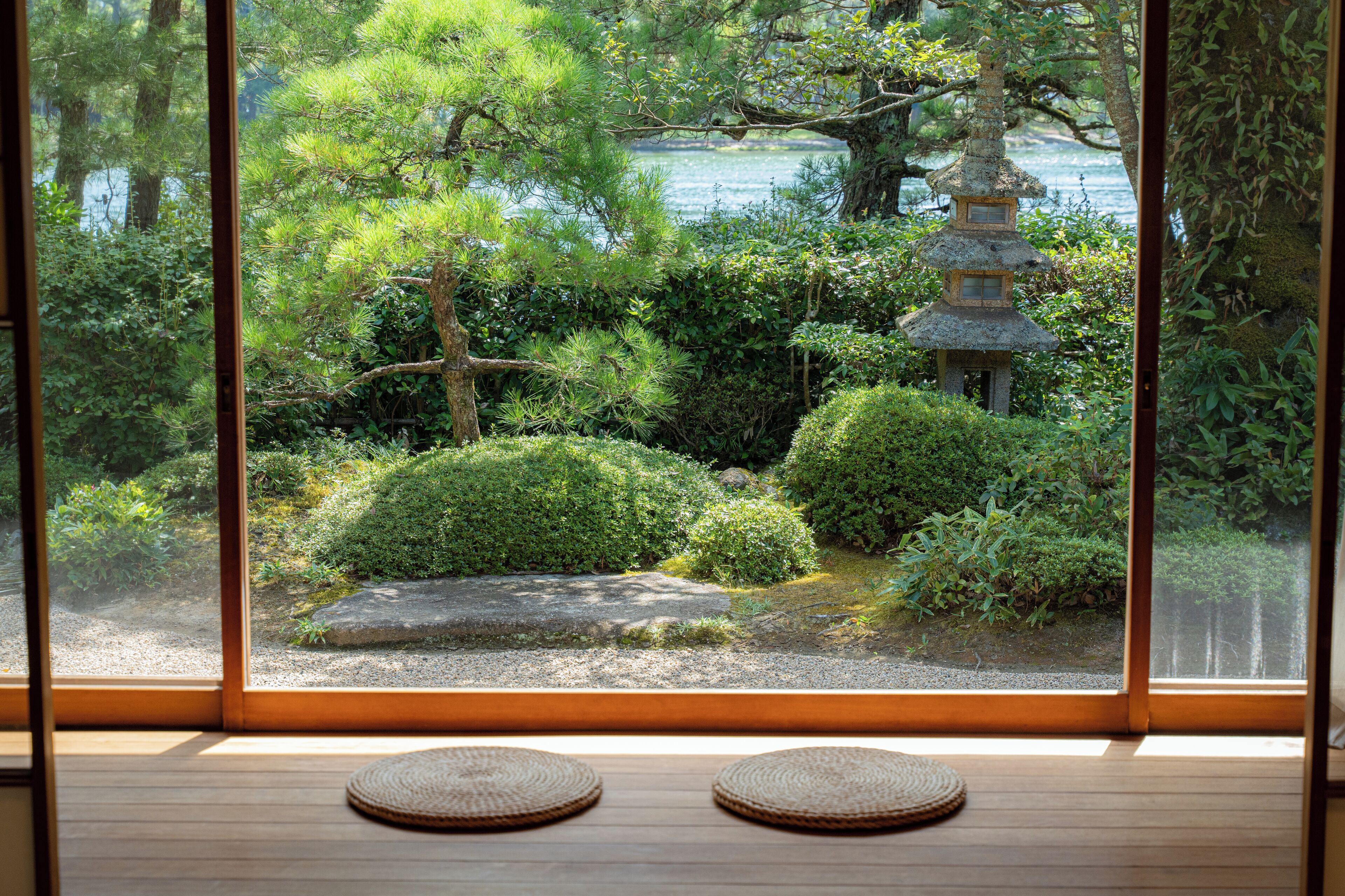 A traditional Japanese room with tatami flooring, a shoji screen, and a view of a serene garden with a pagoda.