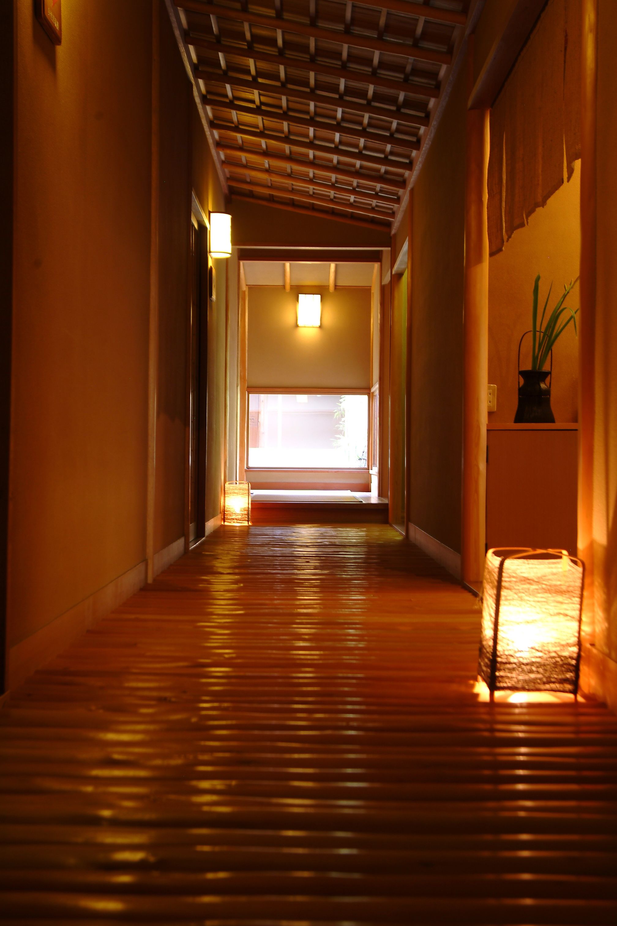 A hallway with a wooden floor and a sloped ceiling.